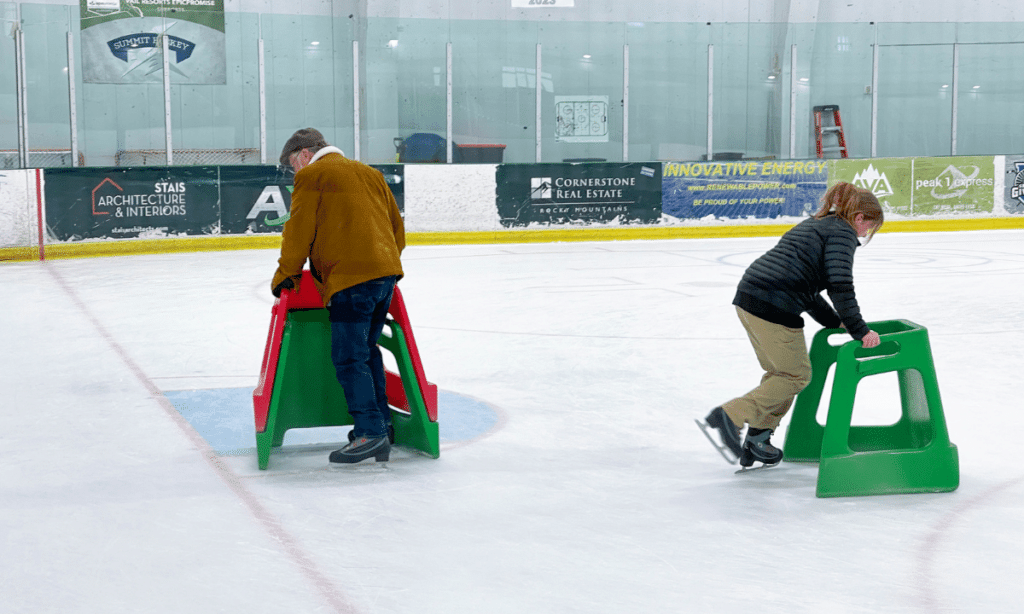 two people learning to skate on an ice rink 